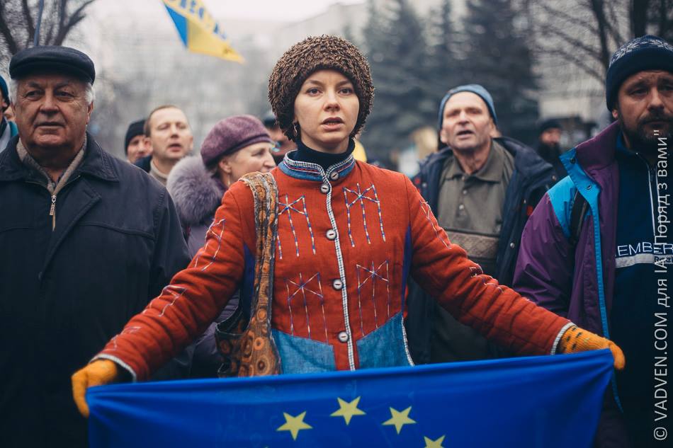 Morozova holding an EU flag wearing red traditional clothes standing in a crowd.
